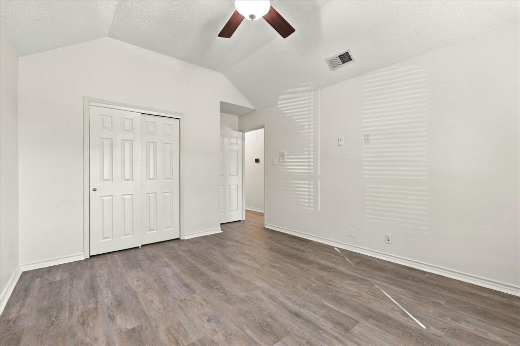 Room featuring vaulted ceilings, wood-finish flooring, and a ceiling fan with integrated lighting
