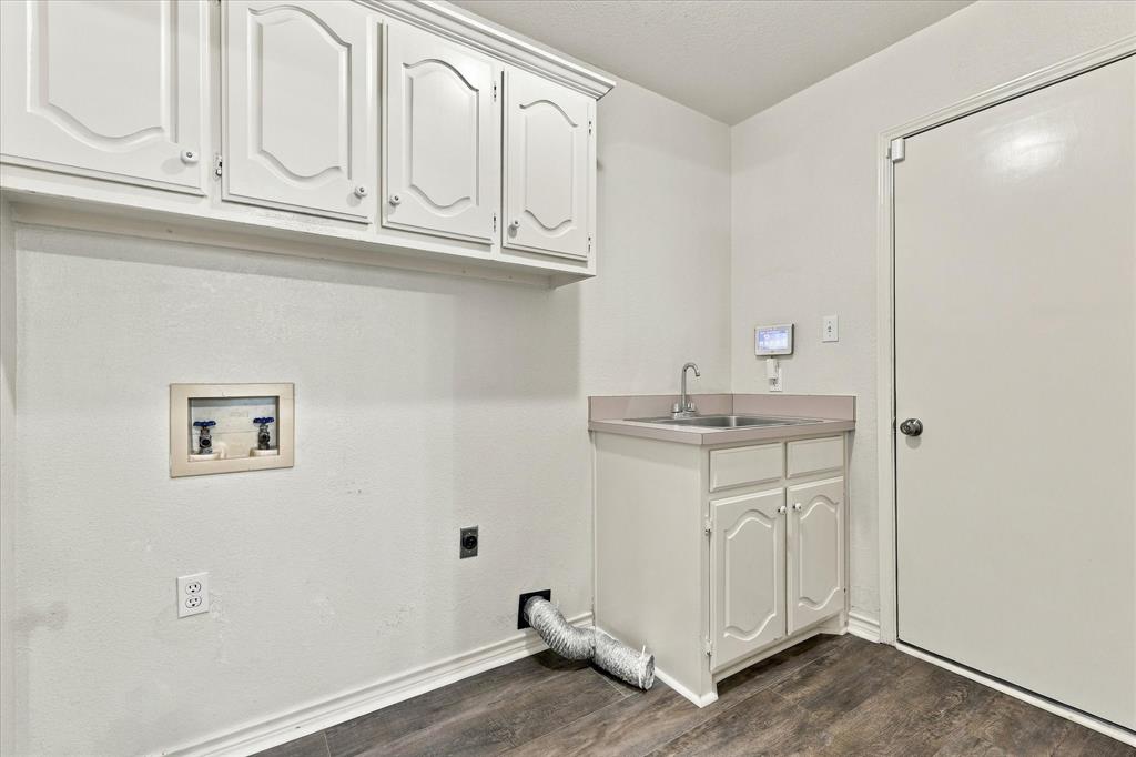 Utility room featuring white cabinetry, a built-in sink with countertop, and wood-finish flooring