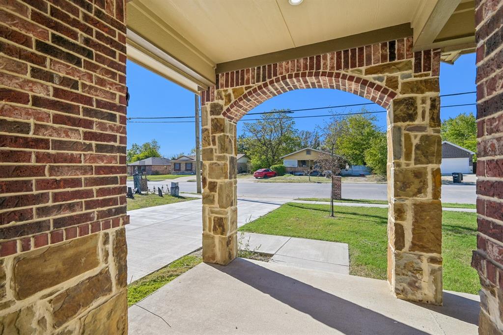 Covered porch featuring stone-clad pillars, arched masonry detailing, and a concrete foundation Covered porch featuring stone-clad pillars, arched masonry detailing, and a concrete foundation
