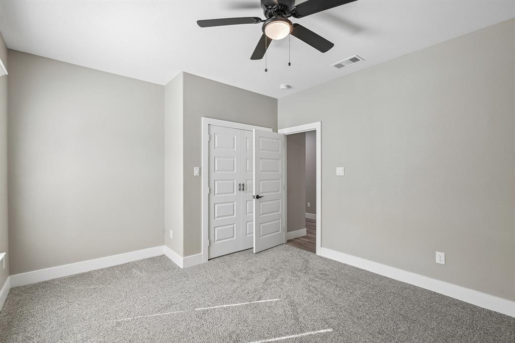 Neutral-toned interior featuring wall-to-wall carpeting, a multi-panel door closet, and a ceiling fan with integrated lighting