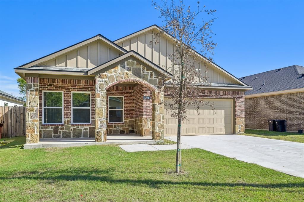 Exterior facade featuring a combination of brick and stone masonry, vertical siding, an arched covered entryway, and an attached two-car garage Exterior facade featuring a combination of brick and stone masonry, vertical siding, an arched covered entryway, and an attached two-car garage