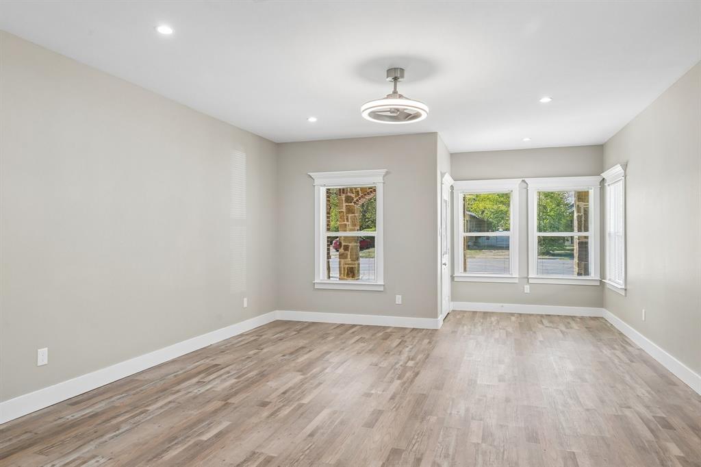 Neutral interior space featuring wood-finish flooring, recessed lighting, a modern ceiling fan, and multiple windows with stone exterior detailing