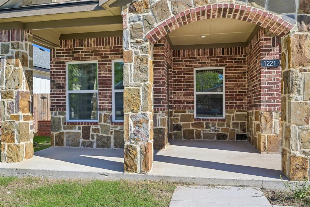 Exterior facade featuring multi-textured stone masonry, red brick accents, an arched covered porch, and columns with stone veneer Exterior facade featuring multi-textured stone masonry, red brick accents, an arched covered porch, and columns with stone veneer