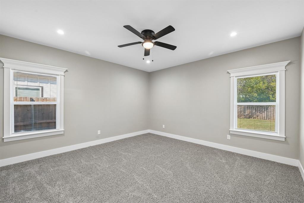 Neutral-toned interior featuring wall-to-wall carpeting, recessed lighting, a ceiling fan with integrated lighting, and dual windows with crown-molding trim