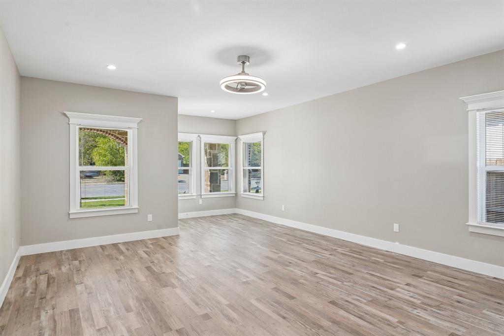 Neutral-toned interior featuring wood-finish flooring, recessed lighting, crown-molding window trim, and a modern circular ceiling fan