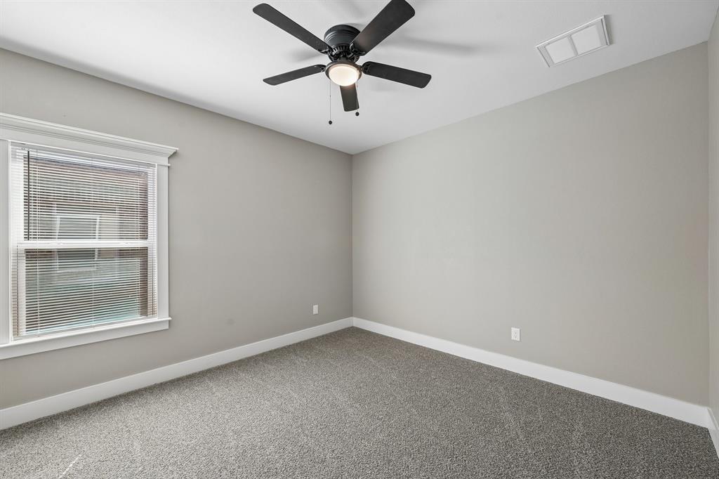 Neutral interior with carpeting, window with decorative trim, and a ceiling-mounted fan with integrated lighting