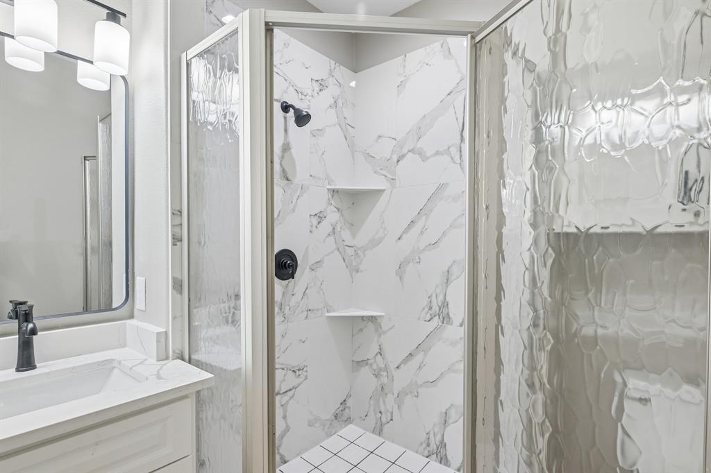 Corner shower enclosure with textured glass doors and stone-patterned tile surrounds