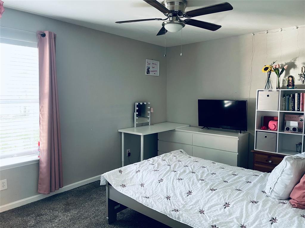 Neutral-toned interior featuring wall-to-wall carpeting, a multi-blade ceiling fan with integrated lighting, and a window with horizontal blinds Neutral-toned interior featuring wall-to-wall carpeting, a multi-blade ceiling fan with integrated lighting, and a window with horizontal blinds
