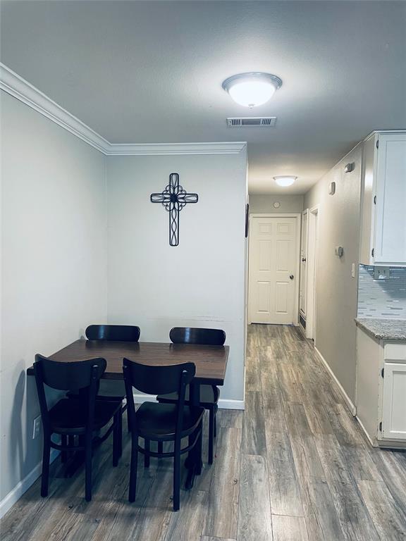 Wood-finish flooring throughout, white shaker-style cabinetry, stone-look countertops, glass tile backsplash, and crown molding Wood-finish flooring throughout, white shaker-style cabinetry, stone-look countertops, glass tile backsplash, and crown molding
