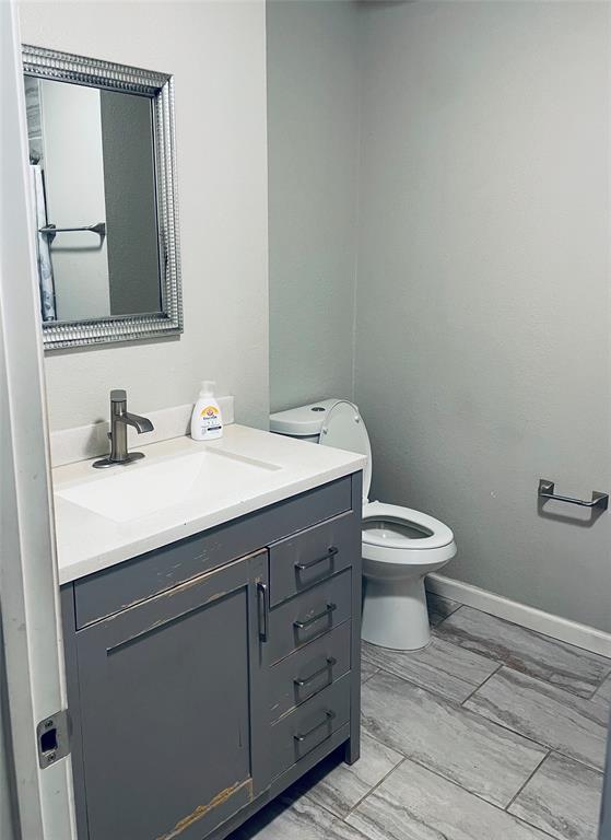 Gray vanity featuring a white solid-surface countertop with an integrated rectangular sink, single-handle brushed-finish faucet, and tile flooring Gray vanity featuring a white solid-surface countertop with an integrated rectangular sink, single-handle brushed-finish faucet, and tile flooring