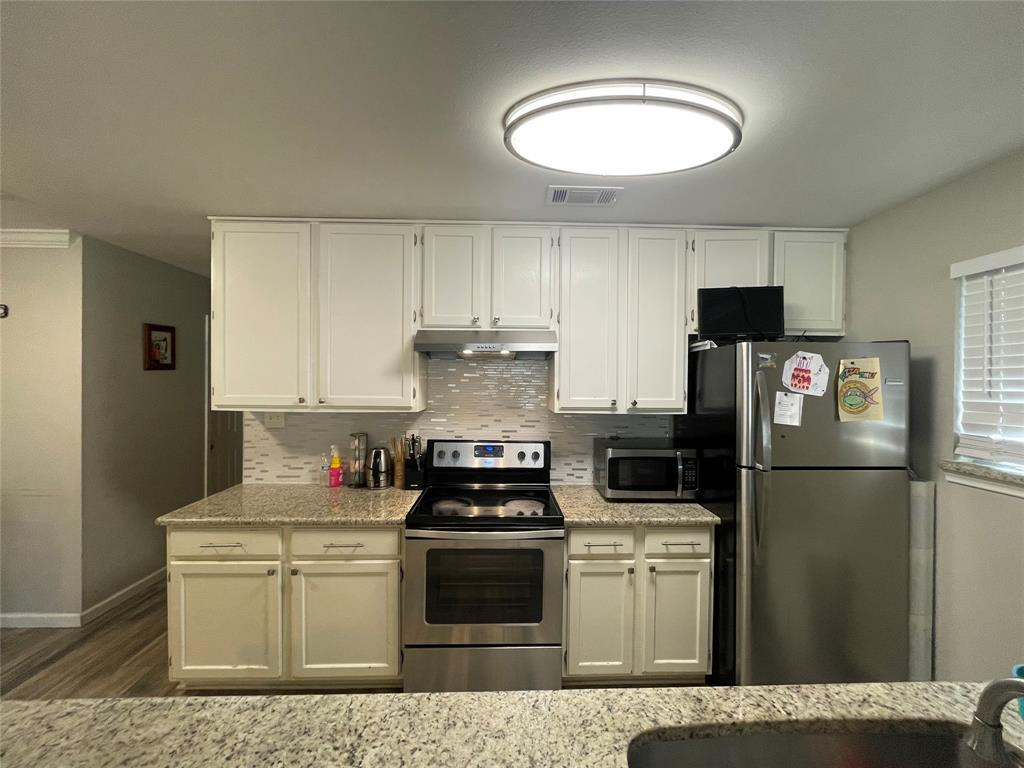 Kitchen featuring white cabinetry, stone-surface countertops, stainless steel appliances, and a tiled backsplash Kitchen featuring white cabinetry, stone-surface countertops, stainless steel appliances, and a tiled backsplash