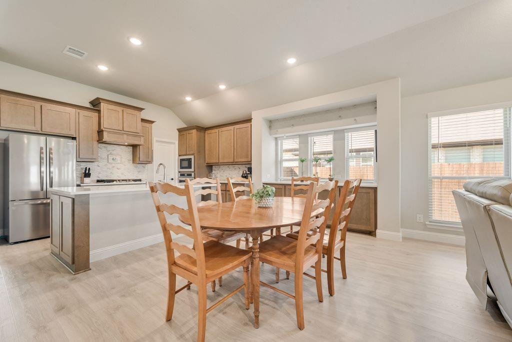 Kitchen featuring wood cabinetry, stainless steel appliances, a central island with quartz countertop, recessed lighting, and wood-finish flooring