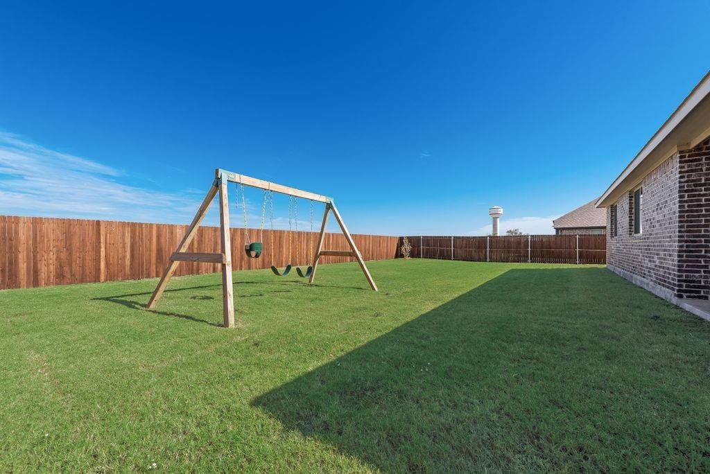 Fenced backyard featuring a manicured lawn and brick exterior wall