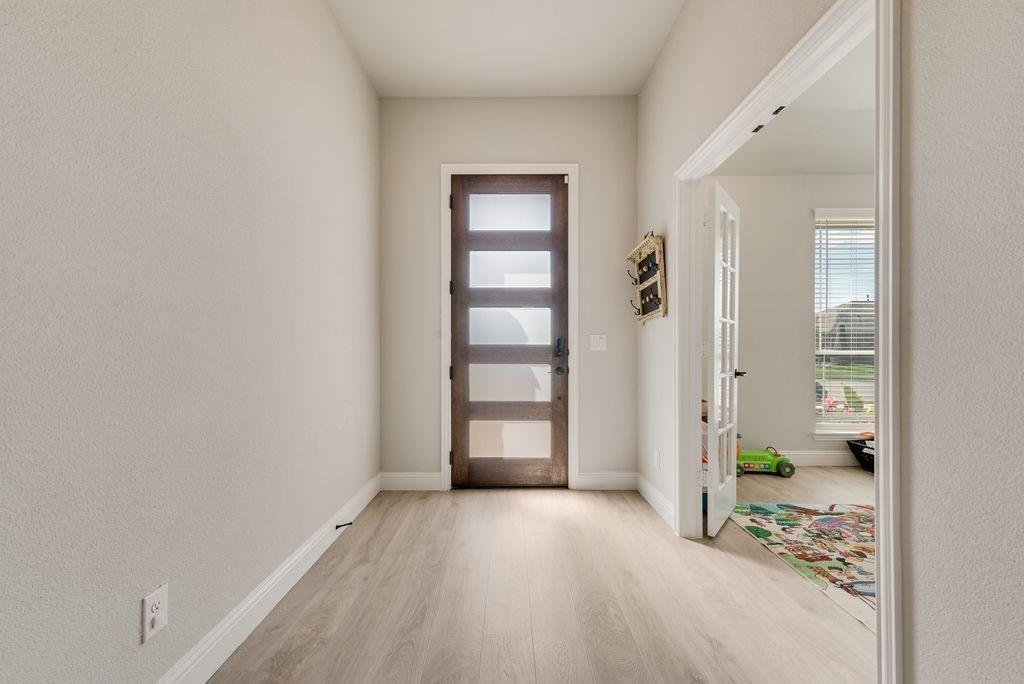 Entryway featuring wood-finish flooring, a contemporary door with five horizontal frosted-glass panels, and a French door with glass panes Entryway featuring wood-finish flooring, a contemporary door with five horizontal frosted-glass panels, and a French door with glass panes