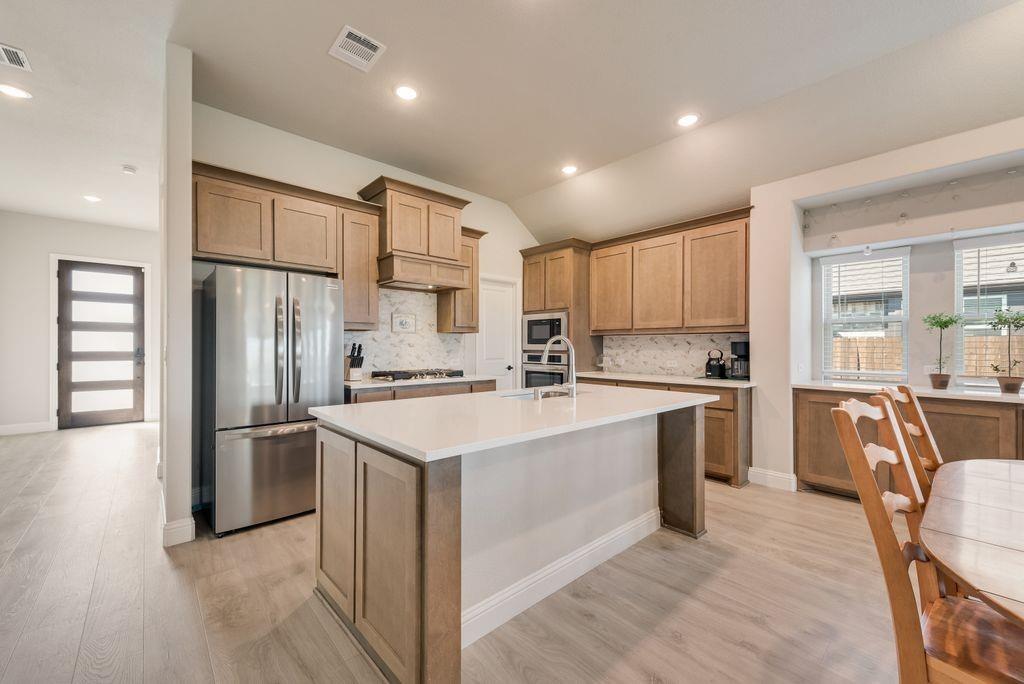Kitchen featuring wood cabinetry, a central island with a quartz countertop, stainless steel appliances, and wood-finish flooring