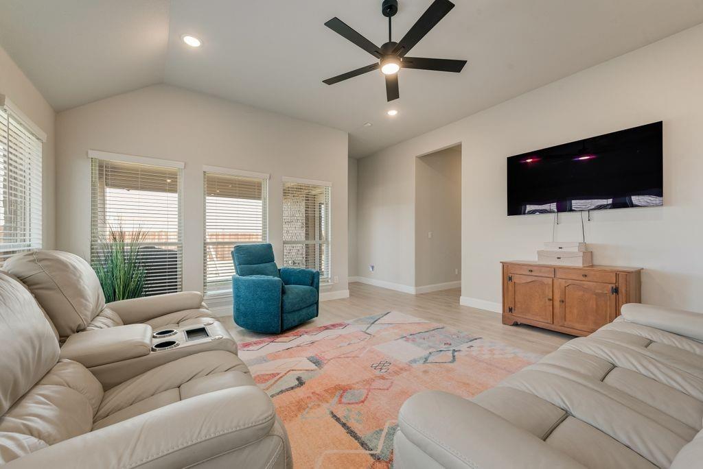 Vaulted ceiling, matte black ceiling fan, wood-finish flooring, and multiple windows with horizontal blinds Vaulted ceiling, matte black ceiling fan, wood-finish flooring, and multiple windows with horizontal blinds