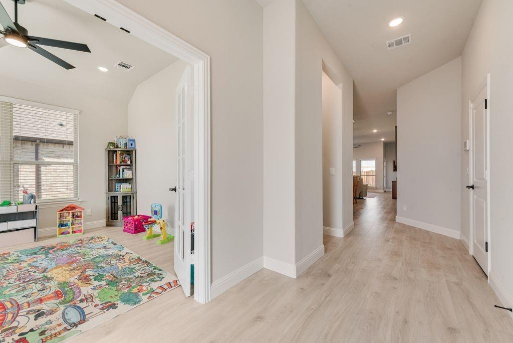 Wood-finish flooring, recessed lighting, ceiling fan with matte black finish, and French doors featuring multi-pane glass inserts Wood-finish flooring, recessed lighting, ceiling fan with matte black finish, and French doors featuring multi-pane glass inserts