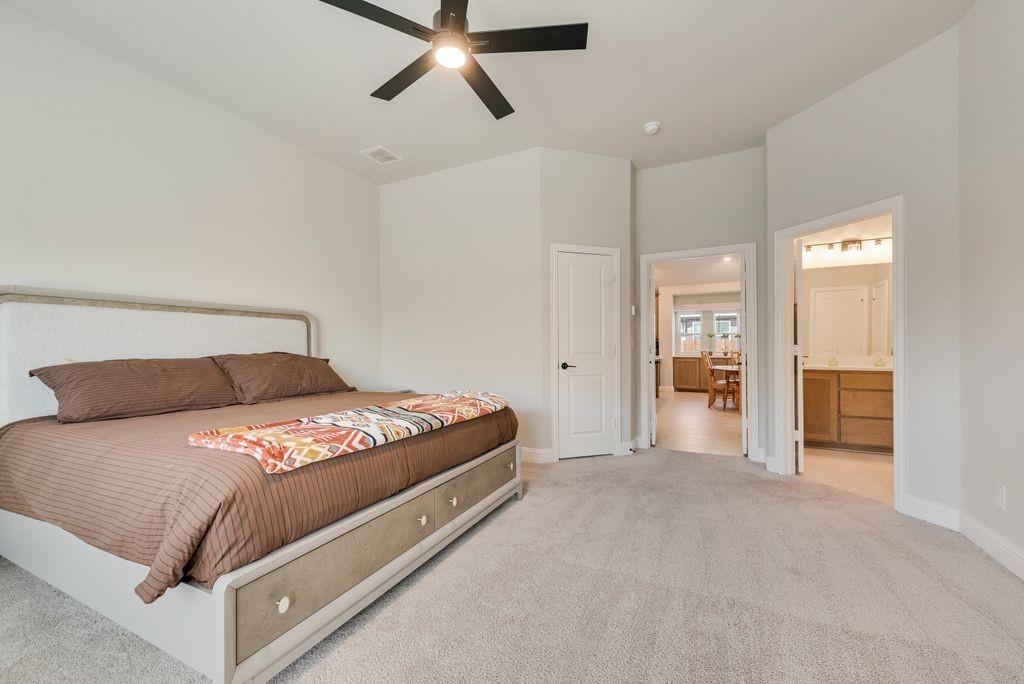Neutral-toned interior space featuring high ceilings, wall-to-wall carpeting, and a multi-blade ceiling fan with integrated lighting
