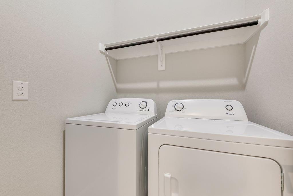 Laundry area featuring a top-load washer, front-load dryer, and an overhead built-in shelving unit with an integrated hanging rod