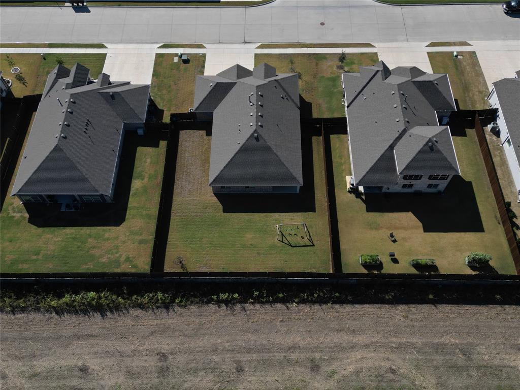 Aerial view of residential properties featuring hip rooflines, concrete driveways, and fenced rear yards