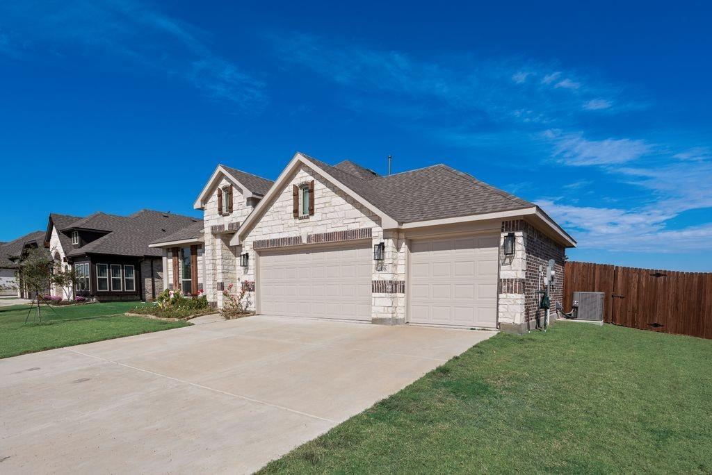 Stone and brick exterior facade featuring a three-car garage, steep roof lines, decorative window shutters, and exterior wall-mounted lighting Stone and brick exterior facade featuring a three-car garage, steep roof lines, decorative window shutters, and exterior wall-mounted lighting