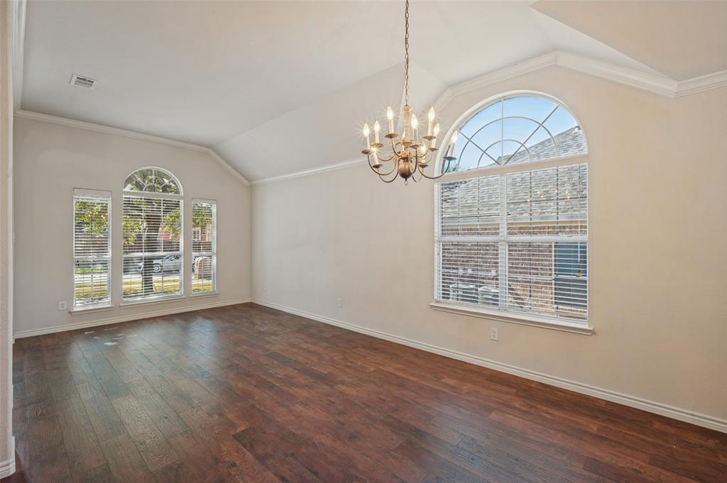 Vaulted ceilings, wood-finish flooring, oversized arched windows, and a multi-arm chandelier