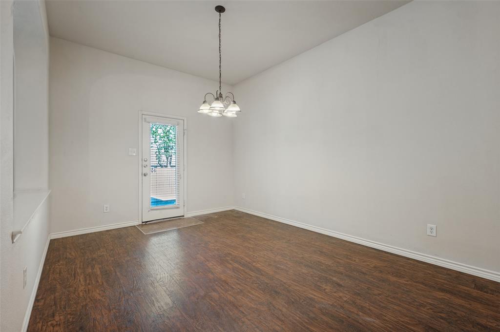 Wood-finish flooring, high ceilings, four-light pendant fixture, and glass-paneled exterior door