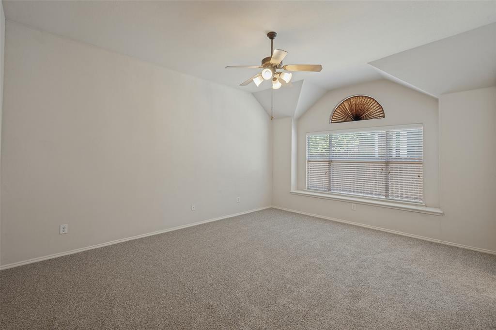 Vaulted ceilings featuring a multi-light ceiling fan and a decorative arched window with a built-in ledge