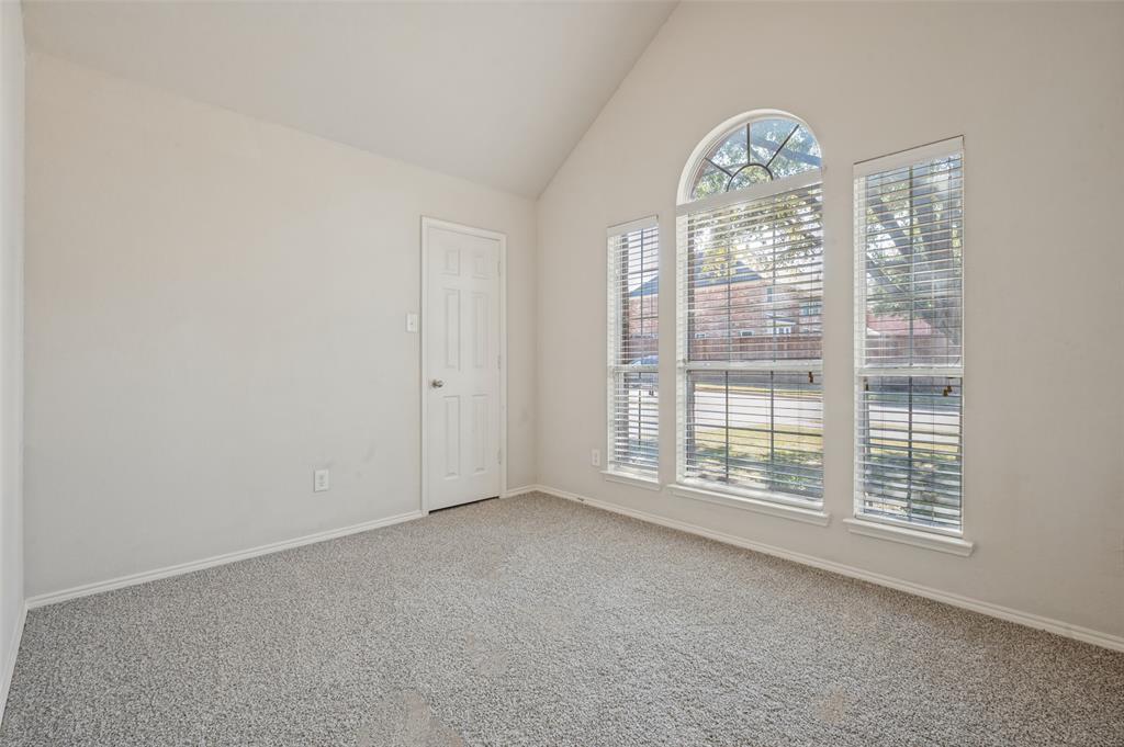 Vaulted ceilings, neutral carpeting, and a prominent arched window assembly with integrated blinds