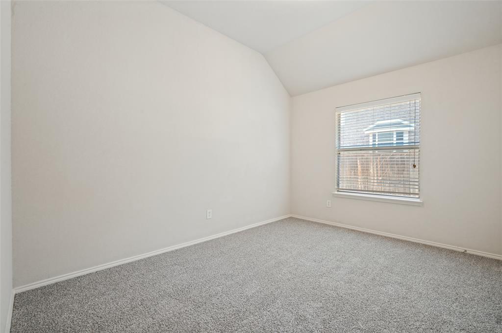 Vaulted ceiling, neutral wall tones, and wall-to-wall carpeting with a single window featuring horizontal blinds