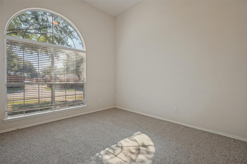 High-vaulted ceiling room featuring a large arched window and neutral carpeting