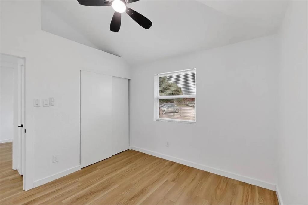 Room featuring vaulted ceilings, wood-finish flooring, a sliding-door closet, and a ceiling fan