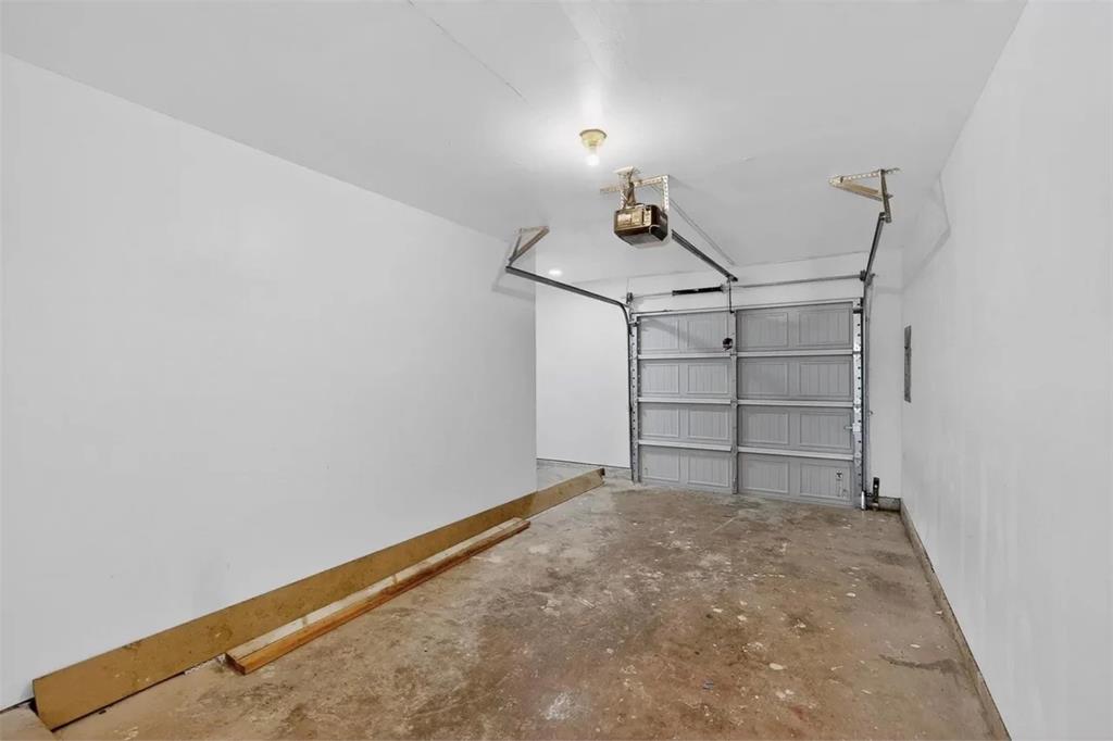 Enclosed garage featuring a sectional metal door, automated door opener, and finished walls
