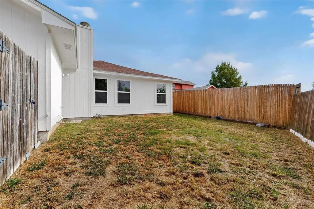 Exterior elevation featuring white vertical siding, a composition shingle roof, and a fenced-in backyard area