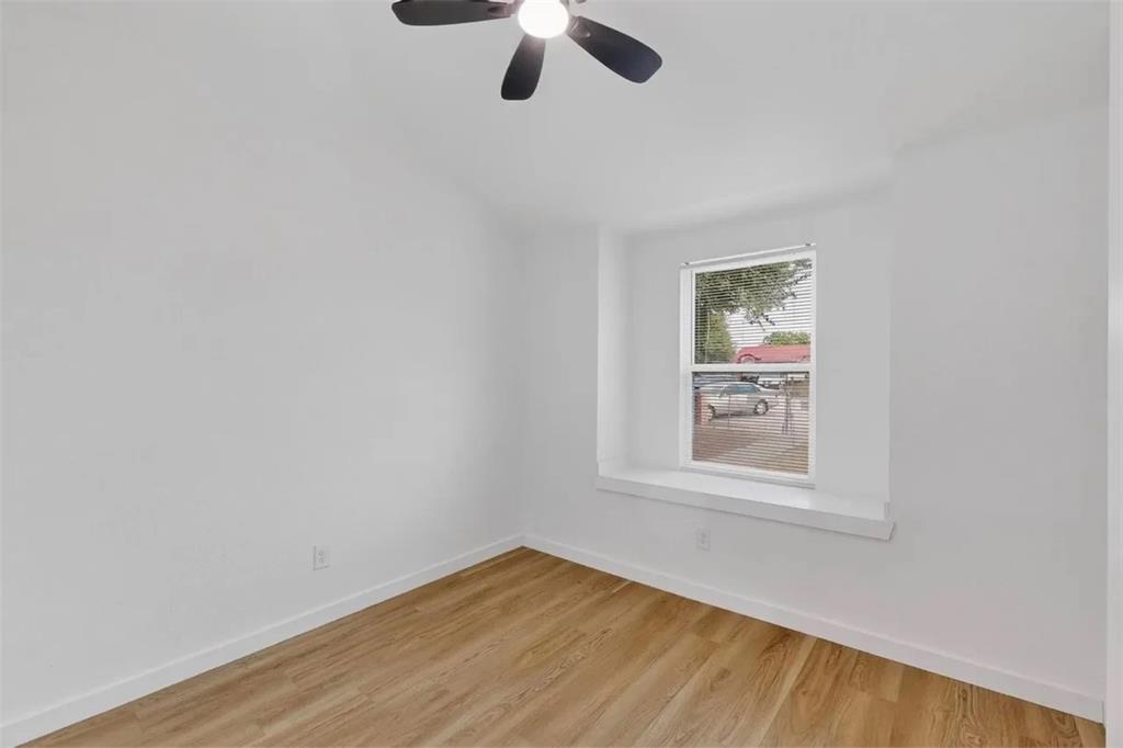 Interior space featuring wood-finish flooring, a recessed window with a built-in ledge, and a ceiling-mounted light fixture with an integrated fan