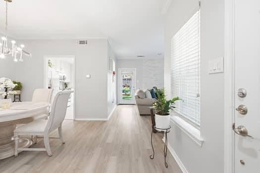 Interior space featuring wood-finish flooring, a multi-light chandelier, horizontal window blinds, and a glass-paneled entry door Interior space featuring wood-finish flooring, a multi-light chandelier, horizontal window blinds, and a glass-paneled entry door