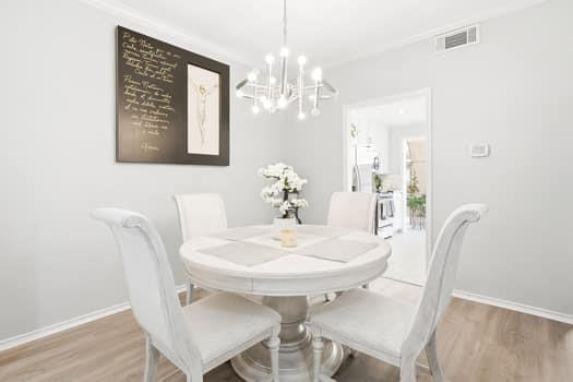 Multi-arm metallic chandelier featuring exposed bulbs, wood-finish flooring, and crown molding Multi-arm metallic chandelier featuring exposed bulbs, wood-finish flooring, and crown molding