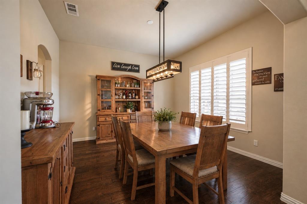 Wood-finish flooring, plantation shutters, and a rectangular multi-light pendant fixture