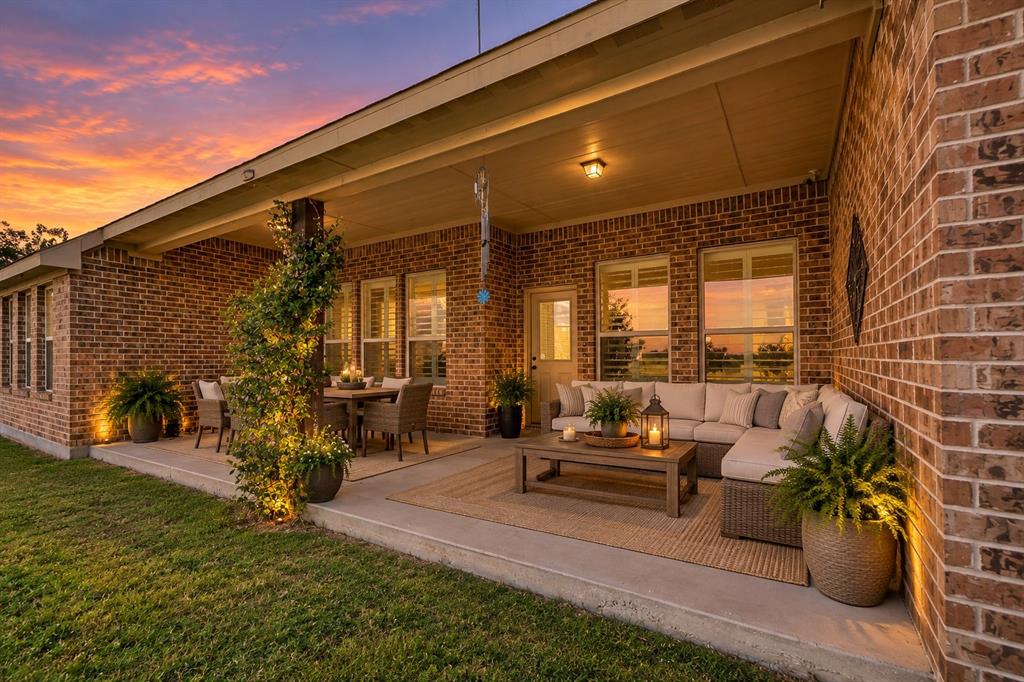 Covered concrete patio featuring full-brick exterior walls, recessed ceiling lighting, and multiple window placements