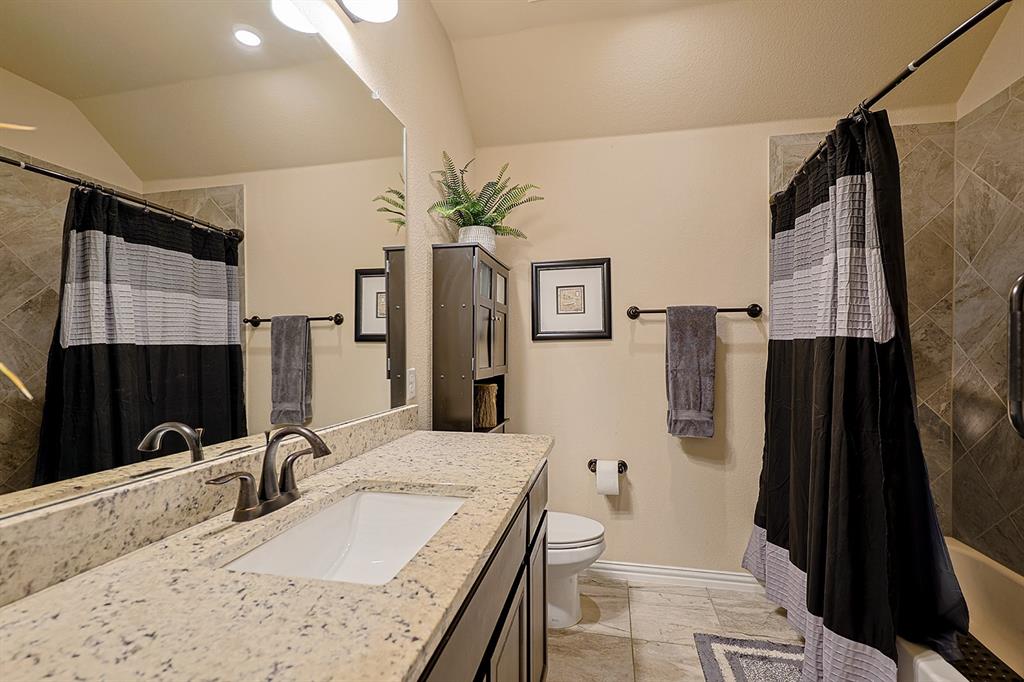 Bathroom featuring a stone-composite countertop with an integrated rectangular sink, oil-rubbed bronze faucet, large wall-mounted mirror, and tile-surround bathtub