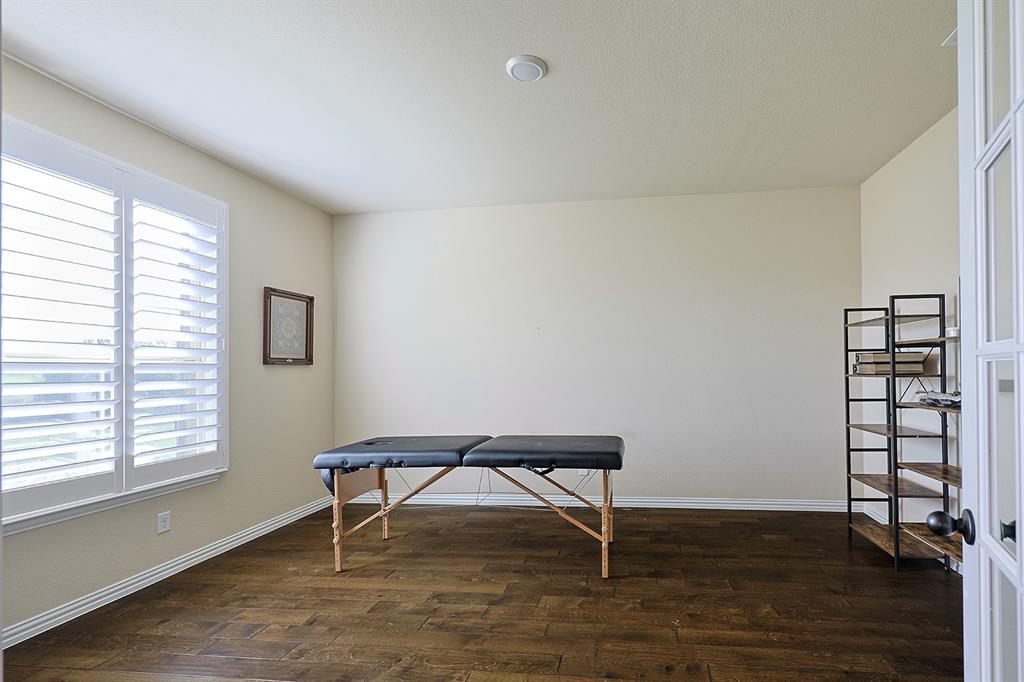 Interior room featuring dark wood-finish flooring, white plantation shutters, and glass-paneled French doors