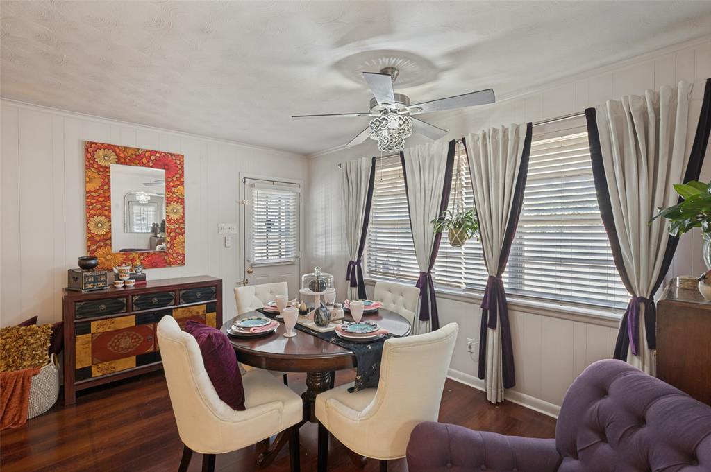 The dining space has a decorative chandelier fan, window coverings, and easy access to the back patio.