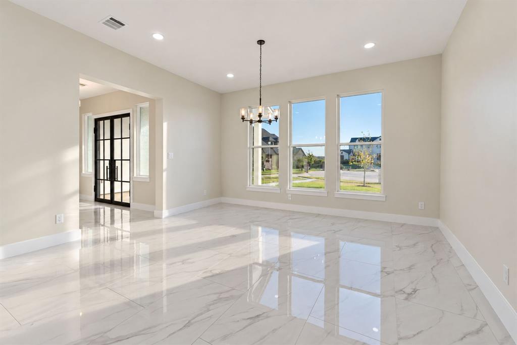 Large format tile flooring, recessed lighting, multi-pane window configuration, and a decorative metal chandelier