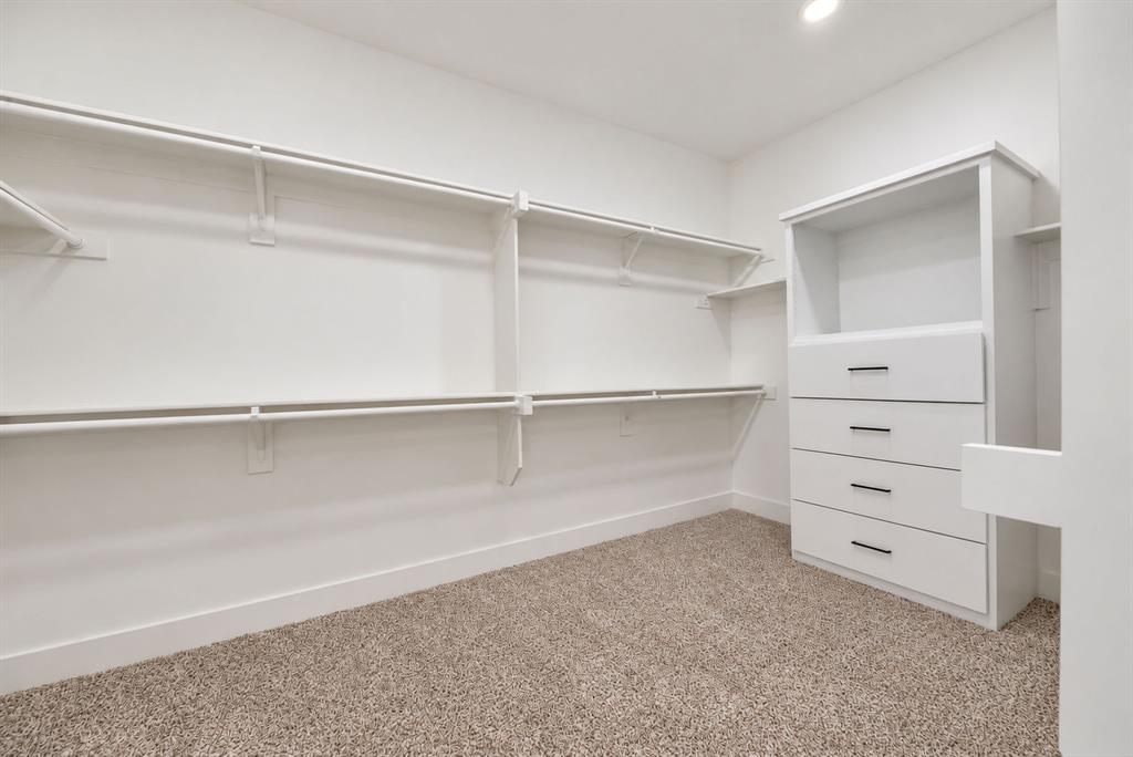 Walk-in closet featuring multi-level hanging rods, built-in cabinetry with four drawers, matte black hardware, and wall-to-wall carpeting