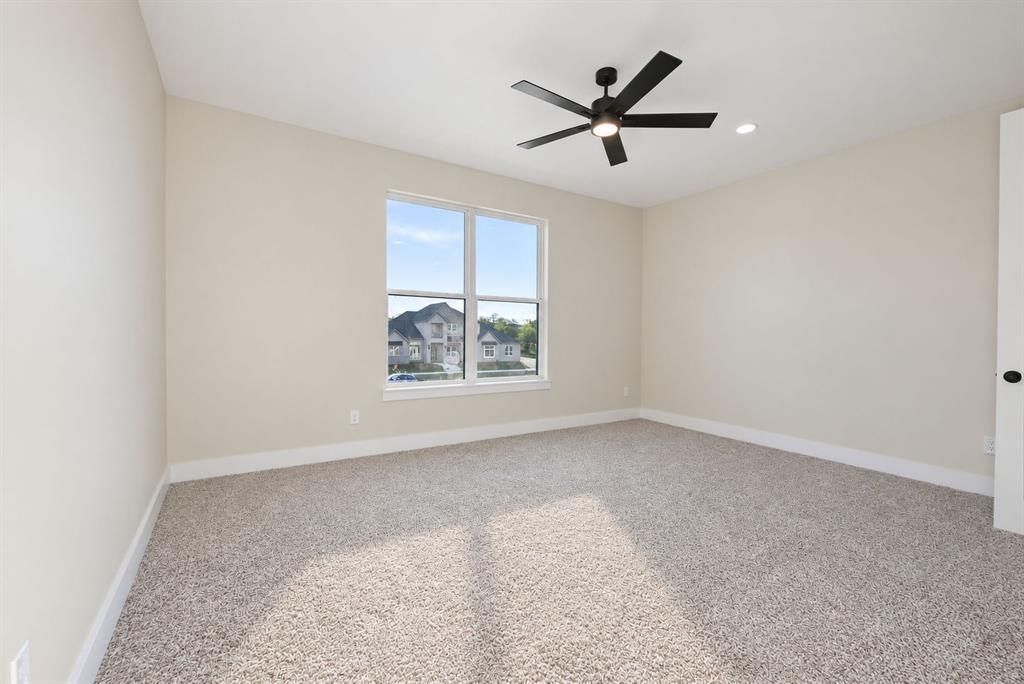 Neutral-toned interior space featuring wall-to-wall carpeting, a multi-pane window, and a matte black ceiling fan with an integrated light fixture