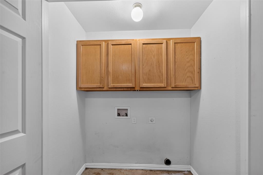 Utility area featuring wood-finish wall-mounted cabinetry, a recessed utility box, and integrated electrical and plumbing connections