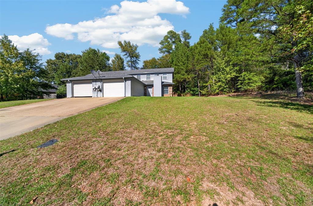 Multi-level exterior featuring horizontal siding, a two-car garage, an asphalt driveway, and a partially wooded lot
