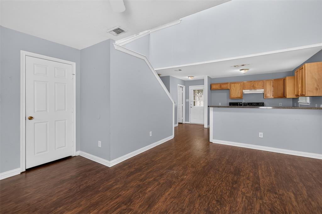 Vaulted ceiling with open mezzanine, wood-finish flooring, and kitchen featuring an extended breakfast bar and wood cabinetry