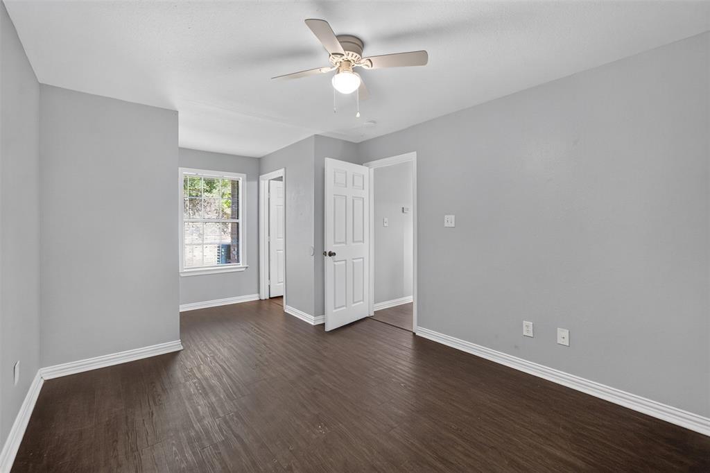 Interior space featuring neutral wall paint, wood-finish flooring, a ceiling fan with light fixture, and a multi-pane window