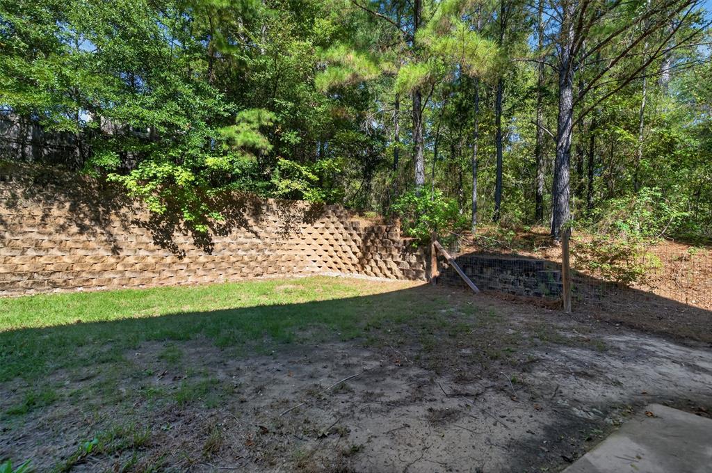 Backyard featuring a tiered stone retaining wall and mature perimeter trees